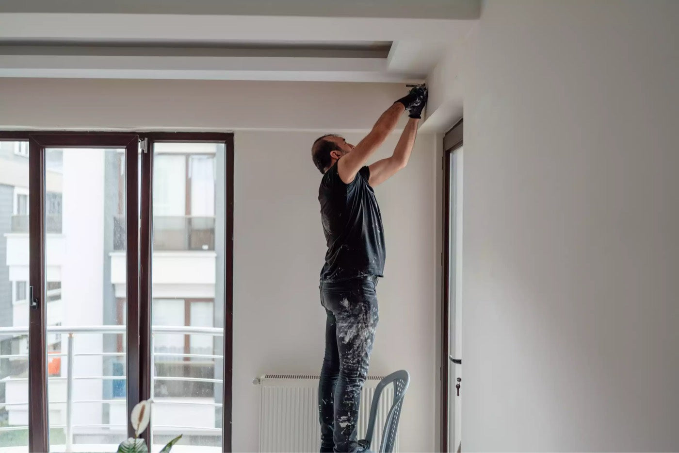 A painter cutting in a clean line where the wall meets the ceiling